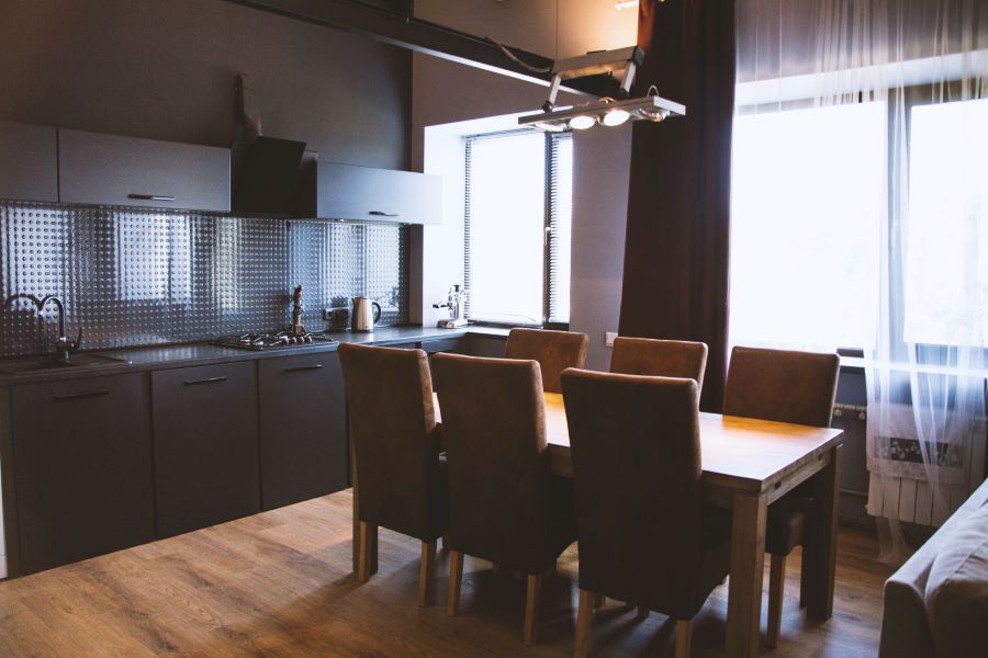 shot-wooden-table-with-wooden-chairs-near-window-curtains-kitchen-with-black-interior